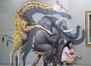 a painted giraffe and elephant at a woman's back